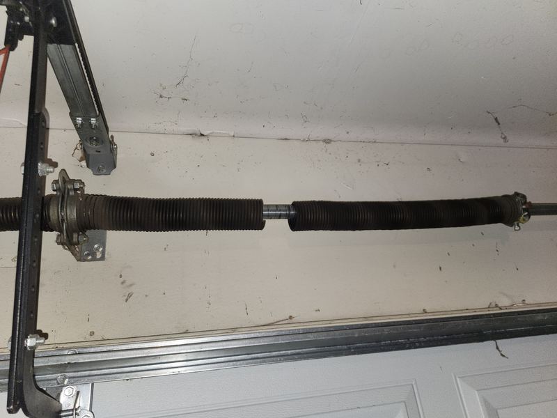 Broken torsion spring with a visible gap before replacement in Dallas, TX