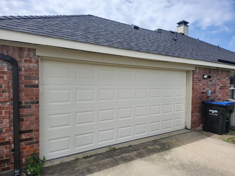 New white raised-panel double garage door on a brick home in Caddo Mills, TX