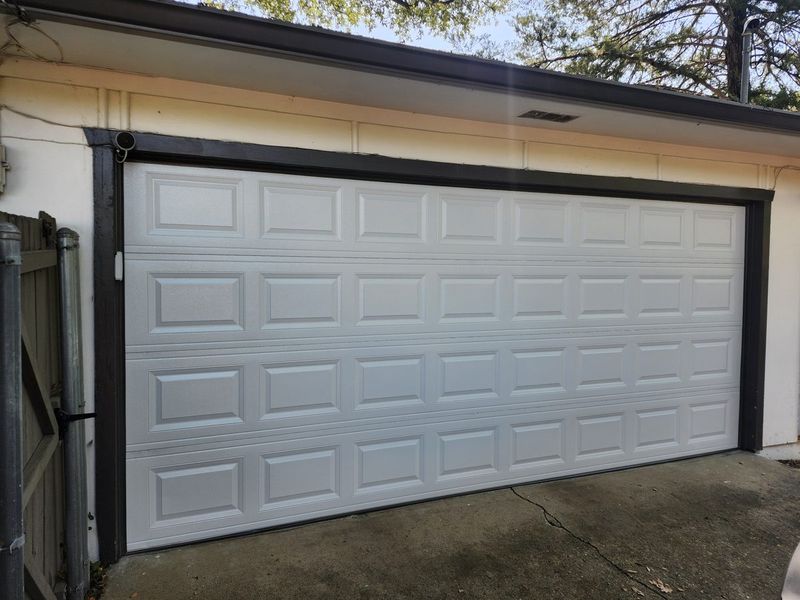 New white raised-panel double garage door with dark trim installed in Dallas, TX