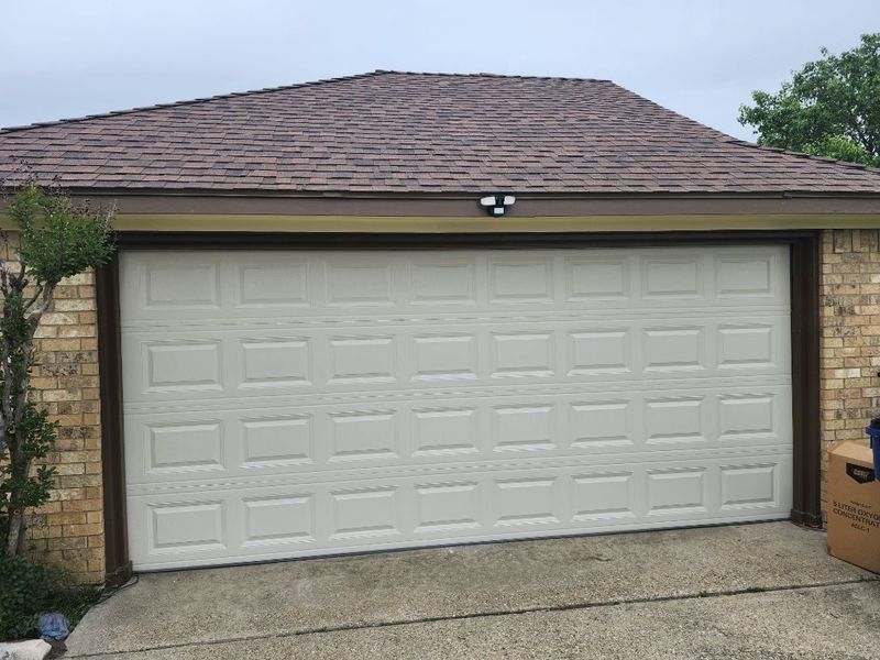 New white raised-panel double garage door installed on a brick home in Forney, TX