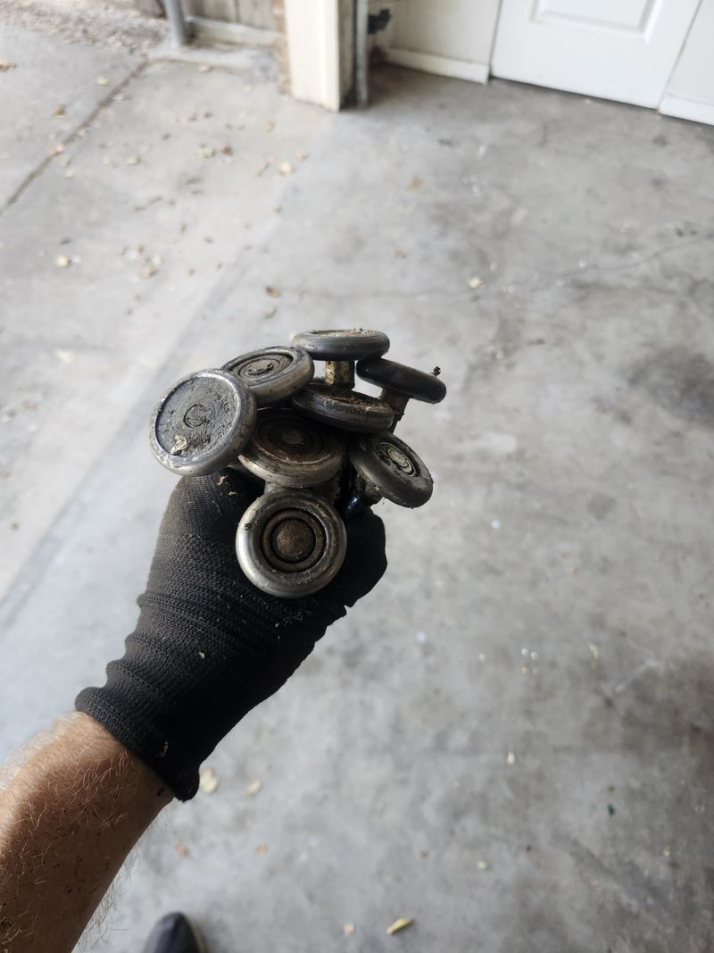 Worn garage door rollers removed during a tune-up in Dallas, TX